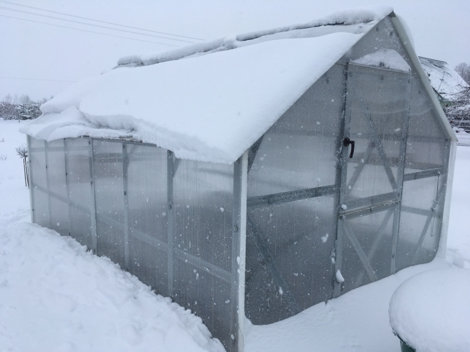 The glasshouse under a heavy winter snowfall, frame and covering intact under the load
